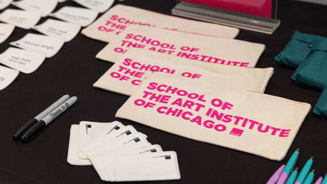 Detial of SCHOOL OF THE ART INSTITUTE OF CHICAGO name tags, stickers, and markers on a table. 