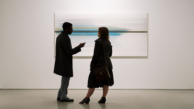 Two silhouettes conversing in a gallery. 