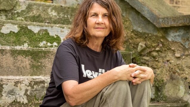 An artist in a black t-shirt sits on dilapidated stone steps