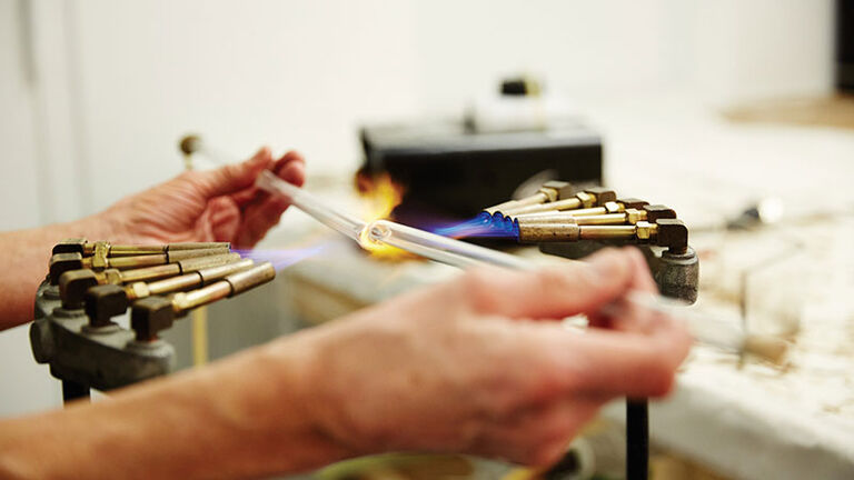 A person welding two clear tubes together.