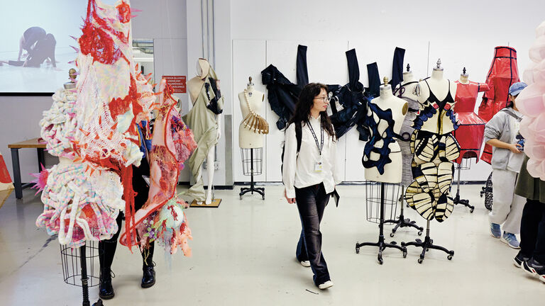 Person exploring a fashion presentation of several garments on mannequins.