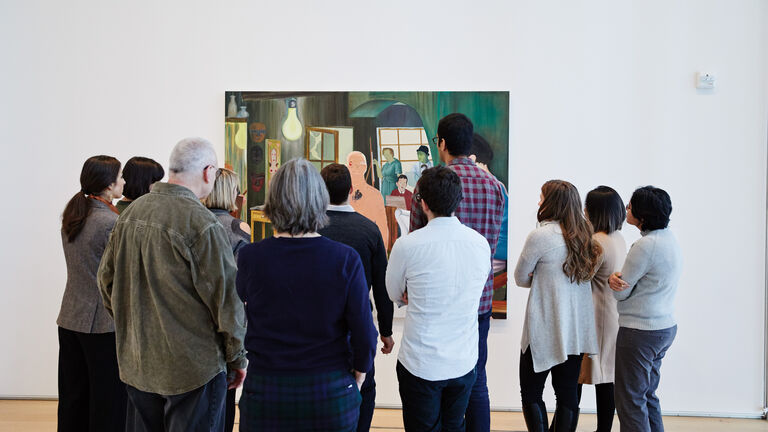 A group of students gathers before a painting in a museum gallery.