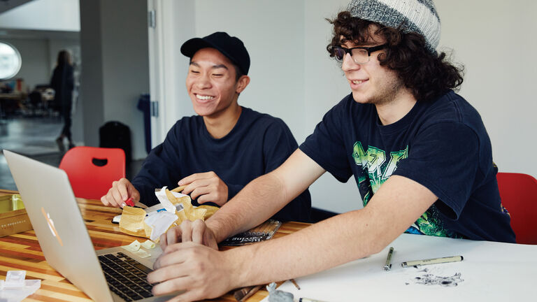 Two students working at a desk. 