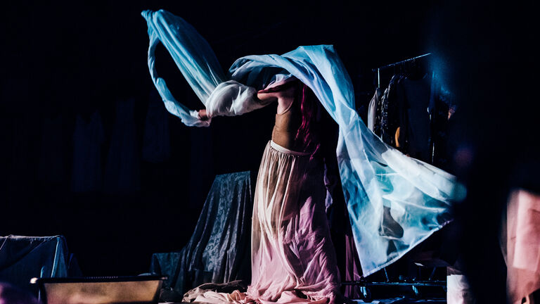 A person performing while draped in sheets