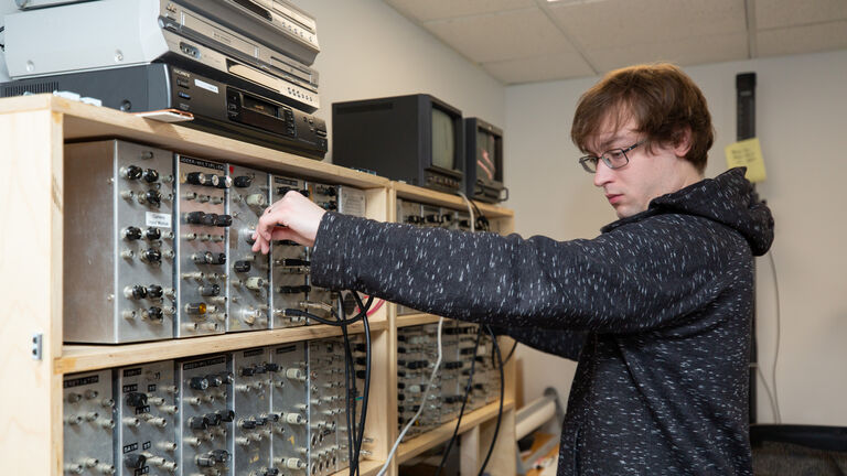 A student using a large switch board. 