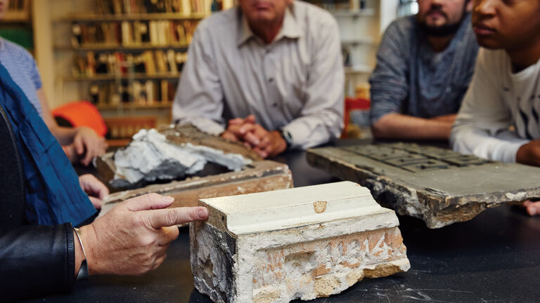 A group of people looking at pieces of a historic structures. 