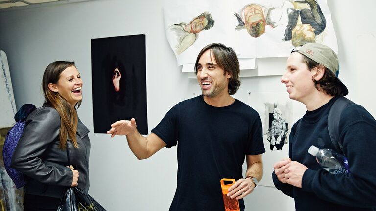 Three students laughing together in a studio room. 