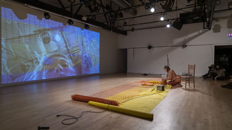 A person sitting on the floor using various materials while being recorded. 