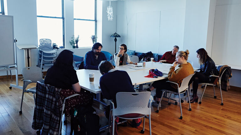 A small group of students sitting at a table having a discussion. 