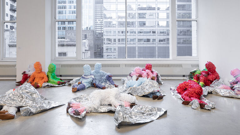 Various paper mache figures laying and sitting ontop of foil. 