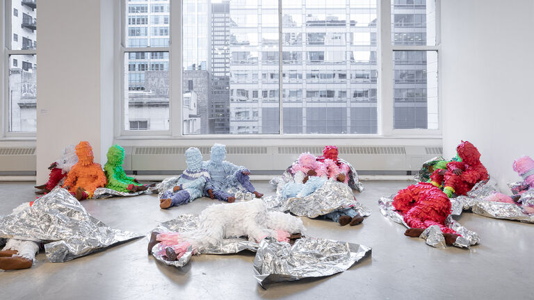 Various paper mache figures laying and sitting ontop of foil. 