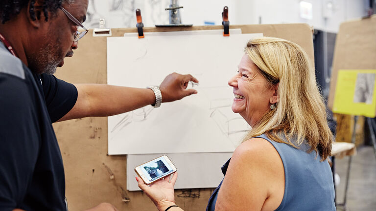 Two people laughing while working on a picture. 