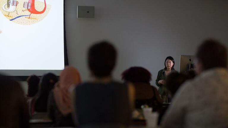 A lecturer standing in front of a large group of students. 