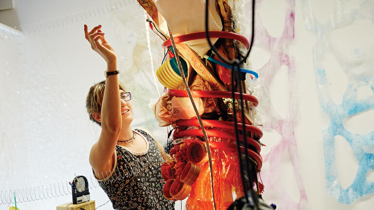 A person working on a large sculpture involving various found materials.