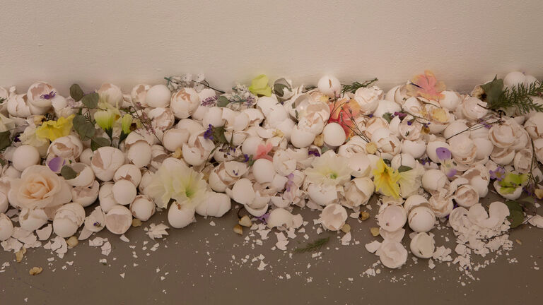 Egg shells and plastic flowers spread out on the ground.