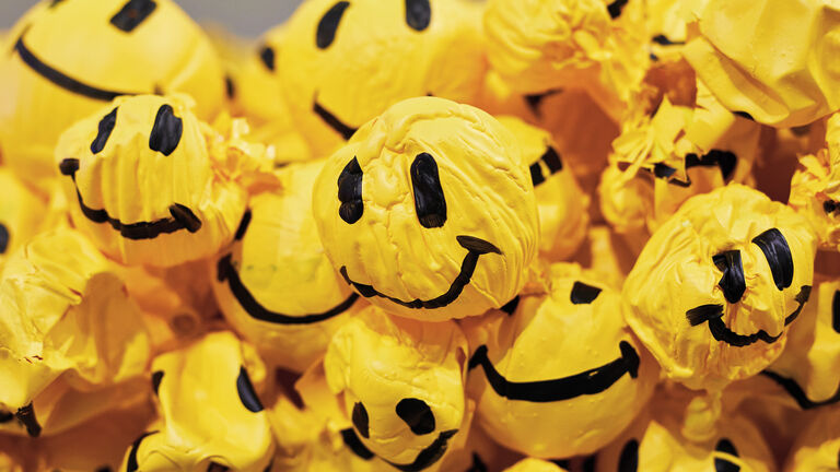 Multiple balloons with smiley faces painted on them in various states of being deflated.