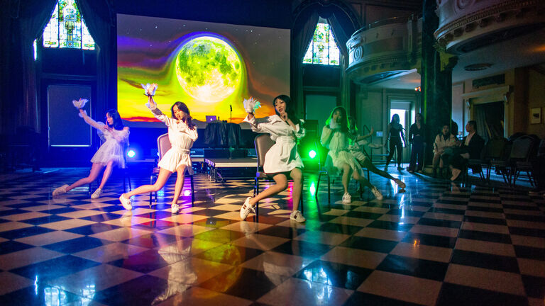 Students dance in front of a projection of the moon at the Chinese Cultural Festival event.