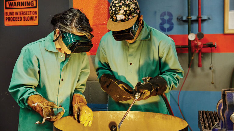 Two students in protective attire in the metal shop