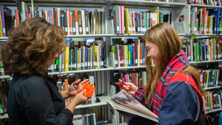 Two students talk and laugh in the library