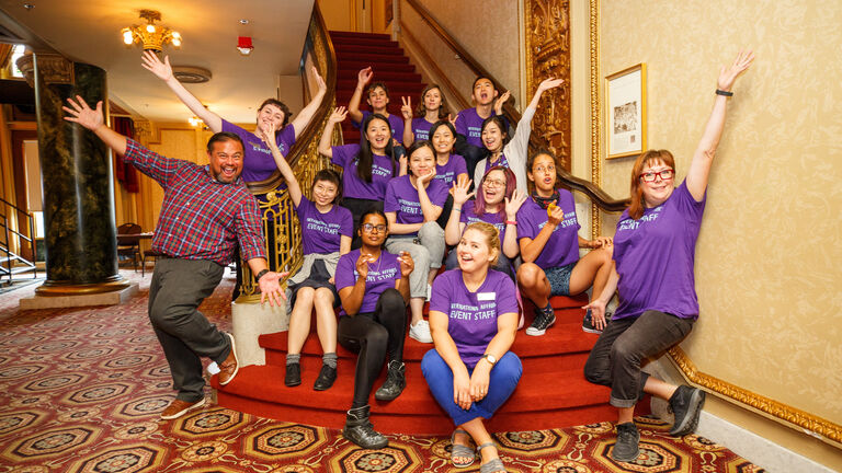 A group of SAIC students exuberantly pose at the bottom of a staircase.