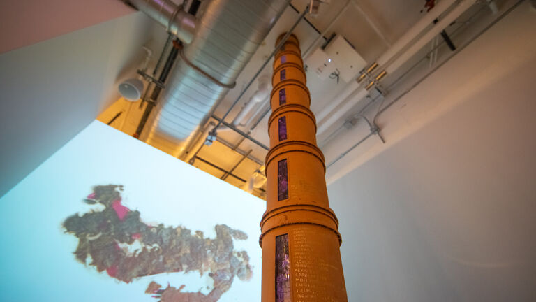 A large orange pillar in a gallery space. 
