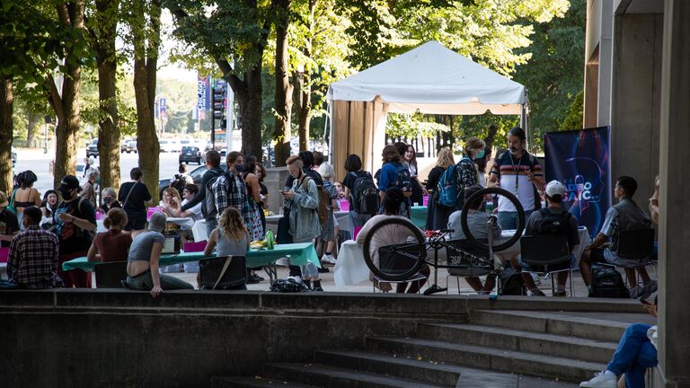 Students outdoors at a fair visiting tables.