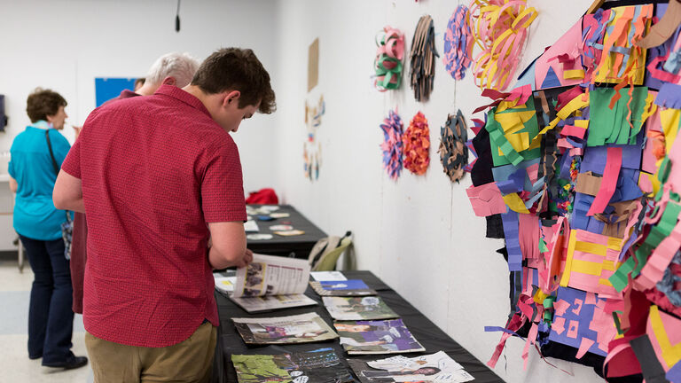 A person looking at a table covered in art projects. 