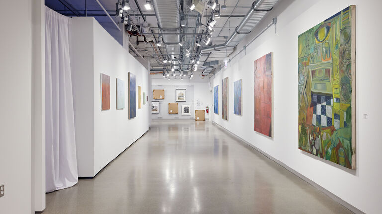 A series of paintings and photos hang on the walls at SAIC Galleries