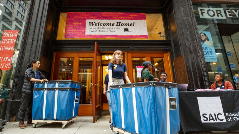 Students wheeling carts in and out of a residence hall