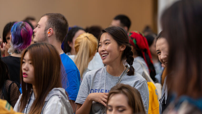 A smiling student in a crowd during Orientation weekend