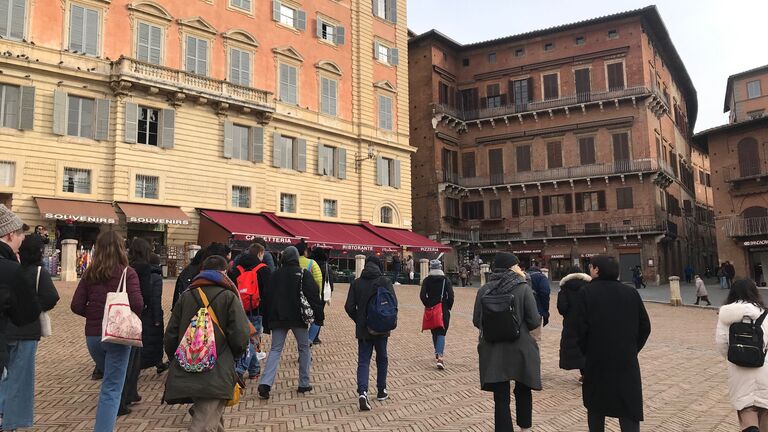 A large group of students walking in a courtyard in Siena, Italy. 