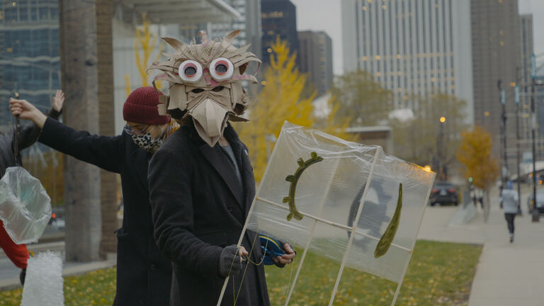 A student outside wearing a bird mask.