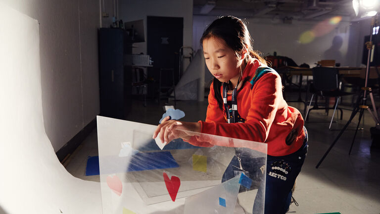 A student tapes shapes to a plexiglass screen