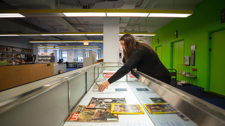 Student leaning over counter installing papers in an exhibition