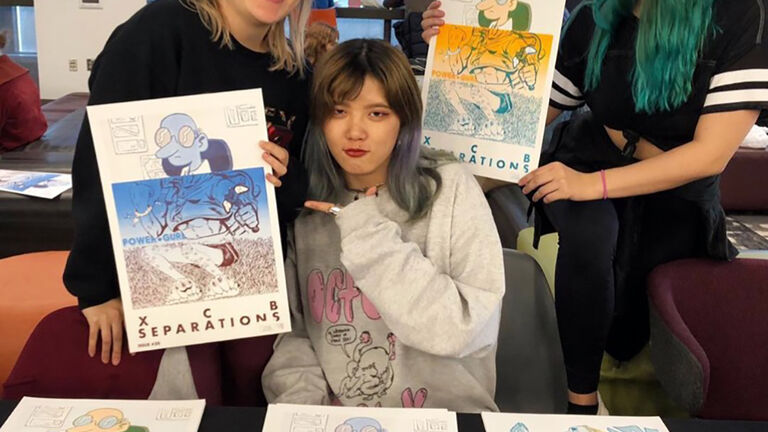 Image of three students holding art.