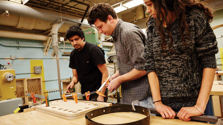 Three students working on a piece in the wood shop.