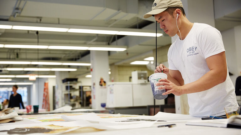 Solo SAIC student painting, over a table in studio space 