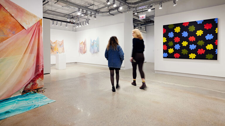 Two students walking around a gallery.