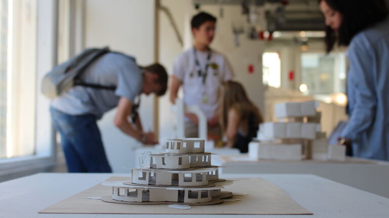 A small model of a building with a group of young students in the background.