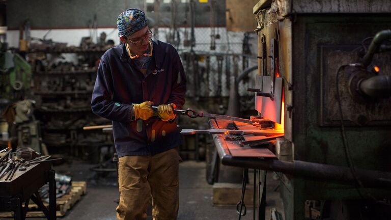 A student in the metal shop working on a piece in a furnace