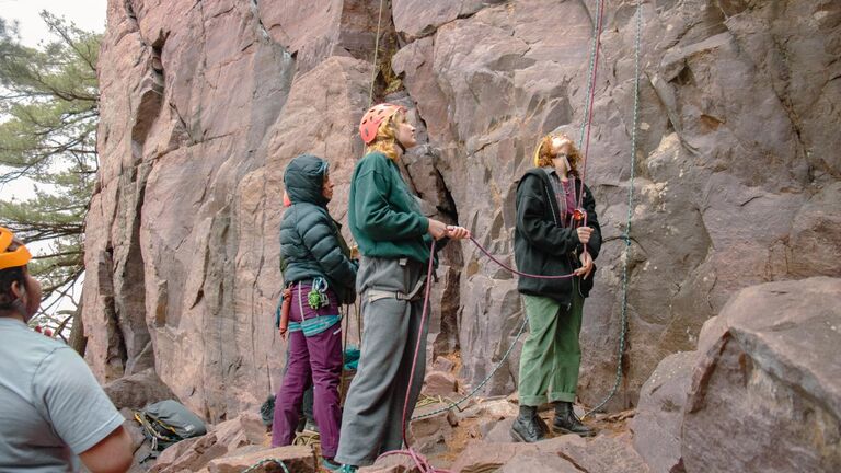 Climbers look up at a rock face
