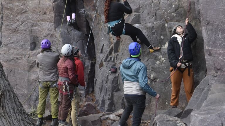 A group of students prepare to climb the side of a mountain