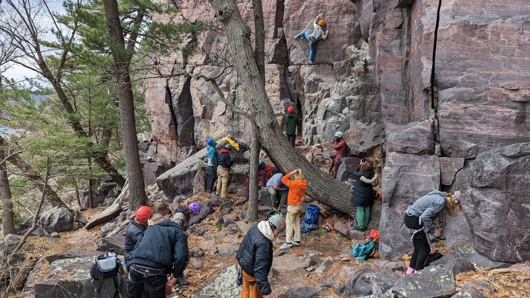 A group of students prepares to scale the side of a mountain