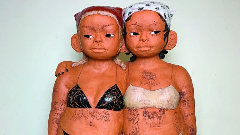 A ceramic statue of two girls with tattoos 