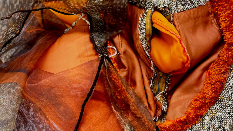 Detail shot of fiber manipulation in orange, biege, brown textiles.