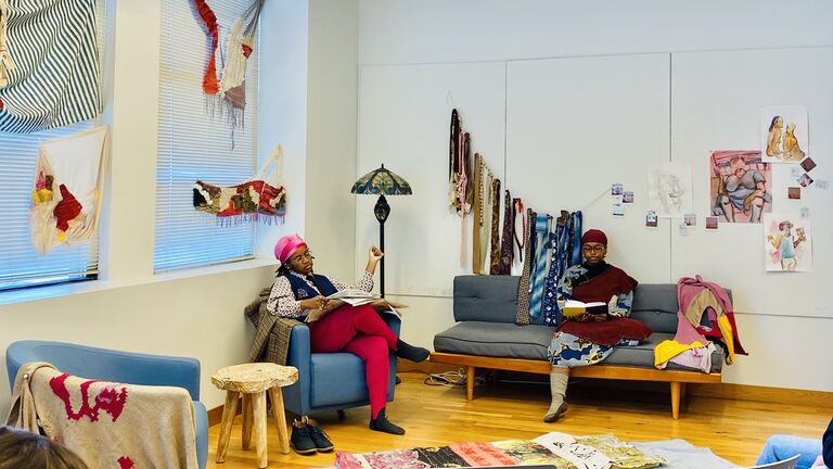 Two women sitting in a room reading.