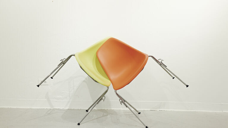 Artwork containing two chairs supporting each other
