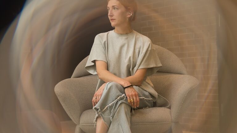 A woman sitting on a chair looking away from the camera with lighting effects around her.