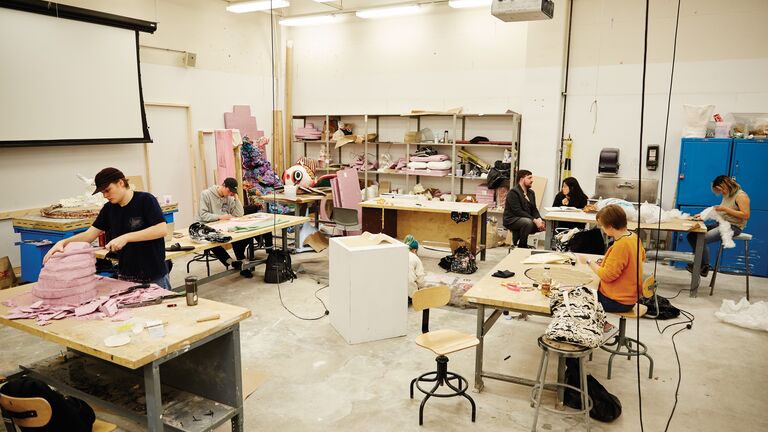 A photo of six sculpture students in a workshop working on their individual projects
