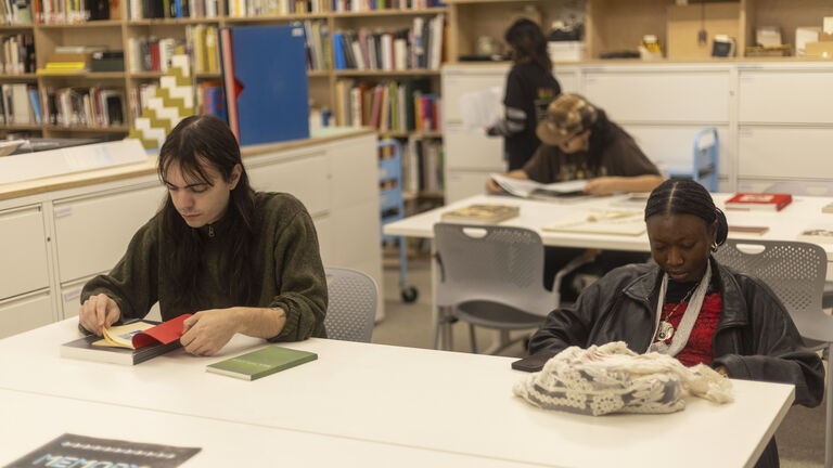 Two students sitting at a table reading at the SAIC library
